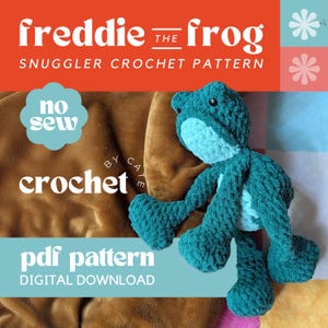 May include: A teal crocheted frog toy with a light blue belly and accents. The image includes text that reads "freddie the frog", "snuggler crochet pattern", "no sew", "crochet", and "pdf pattern digital download". The frog is lying on a brown surface.