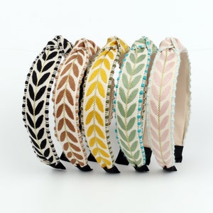 May include: Set of six knotted headbands with a leaf pattern. The headbands are in black, brown, yellow, green, and pink.