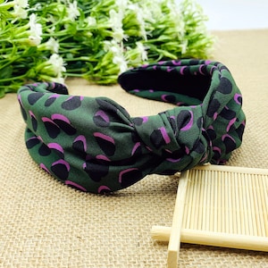 Può includere: Un cerchietto verde e viola annodato con motivo leopardato.