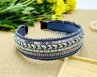 Puede incluir: Una diadema azul con un borde decorativo de cuentas plateadas y doradas, lentejuelas y bordados blancos y beige.