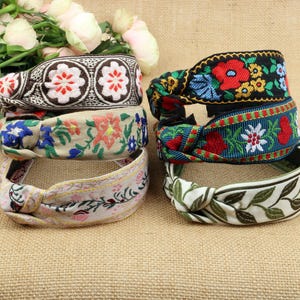 May include: Five colorful fabric headbands with floral and leaf patterns. The headbands are tied in a knot and are made of a soft, woven fabric.