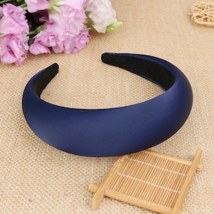 Könnte beinhalten: Ein breites, marineblaues Stirnband aus weichem, gepolstertem Material. Das Stirnband ist so konzipiert, dass es bequem und stylisch ist.
