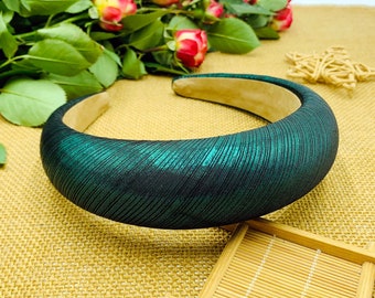 May include: A dark green headband with a satin finish. The headband is wide and has a slightly curved shape.
