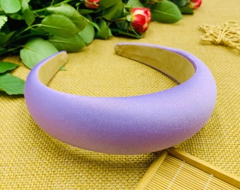 May include: A wide, purple satin headband for women. The headband is smooth and has a slight sheen.
