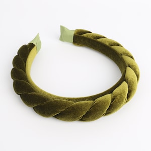 May include: A green velvet headband with a braided design. The headband is made of a soft, plush fabric and is perfect for adding a touch of elegance to any outfit.