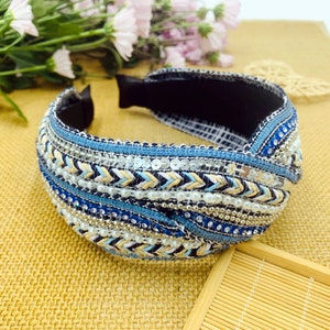 May include: A blue, white, and gold headband with a knotted design and beaded embellishments.
