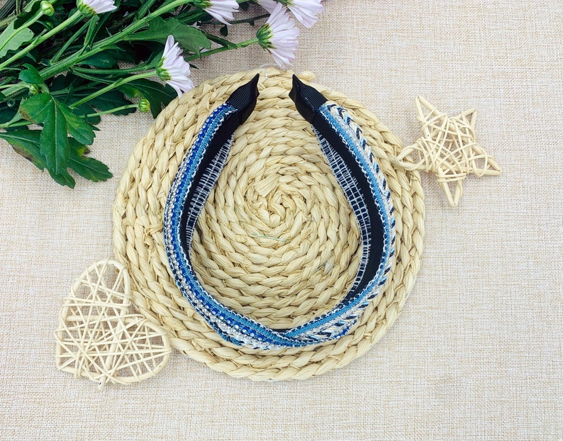 May include: A blue and white patterned headband with a black elastic band. The headband is on a woven straw mat.