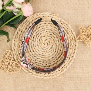 May include: A brown and red patterned headband with a woven straw background.