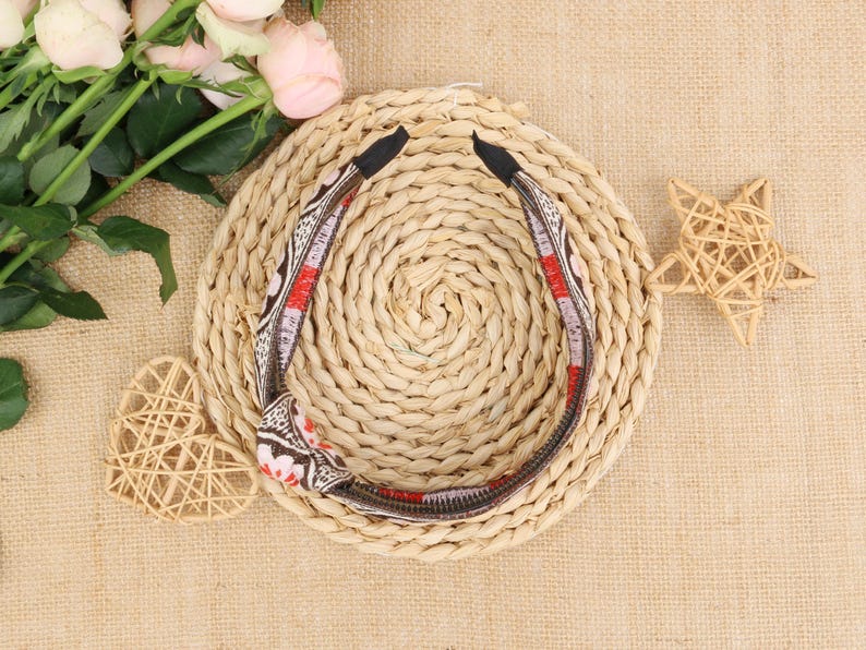 May include: A brown and red patterned headband with a woven straw background.
