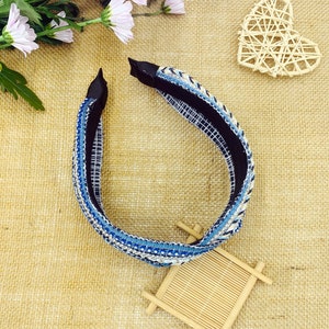 May include: A blue and white headband with rhinestones. The headband is made of a woven fabric and has a black elastic band.