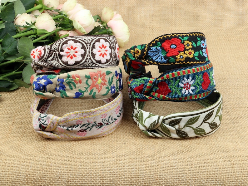 May include: Five colorful fabric headbands with floral and leaf patterns. The headbands are tied in a knot and are made of a soft, woven fabric.