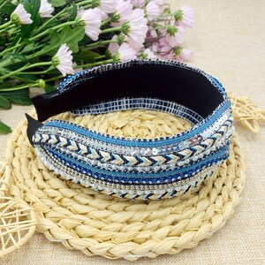 May include: A blue and white headband with a beaded and sequined design. The headband is made of a soft, stretchy material and is perfect for adding a touch of bohemian style to any outfit.