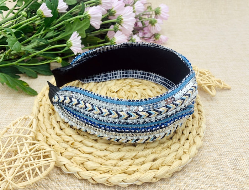 May include: A blue and white headband with a beaded and sequined design. The headband is made of a soft, stretchy material and is perfect for adding a touch of bohemian style to any outfit.