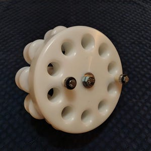 以下が含まれることがあります： 円形のデザインの白い全方向ホイール。小さな丸い穴が複数あり、ボルトで固定されています。このホイールは全方向への動きのために設計されています。