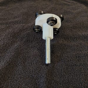 May include: A white plastic base with four black wheels attached to a metal rod. The base is designed to be used as a rotating platform.