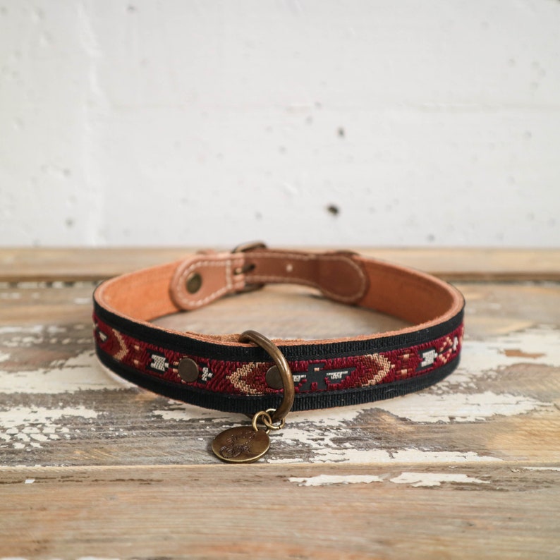 May include: A black and red patterned dog collar with a brown leather base and a brass tag.