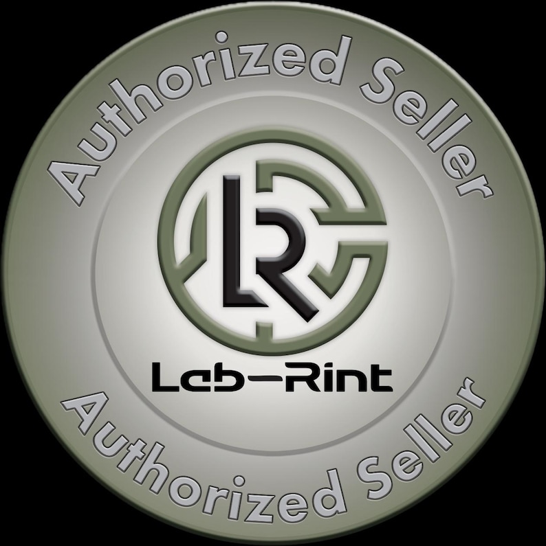 Pu&ograve; includere: Un distintivo circolare con una finitura metallica verde oliva e argento. Il centro mostra un logo nero stilizzato con le lettere LR all'interno di una cornice circolare. Sotto il logo si trova il testo Leb-Rint. Le parole Authorized Seller appaiono due volte.