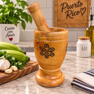 May include: A light brown wooden mortar and pestle set featuring a carved sun-like symbol on the exterior. The mortar has a wide, stable base and a cylindrical body, while the pestle is a long, tapered wooden tool designed for grinding ingredients.