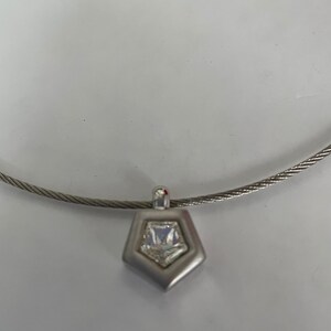 May include: A silver necklace with a geometric pendant featuring a clear crystal.