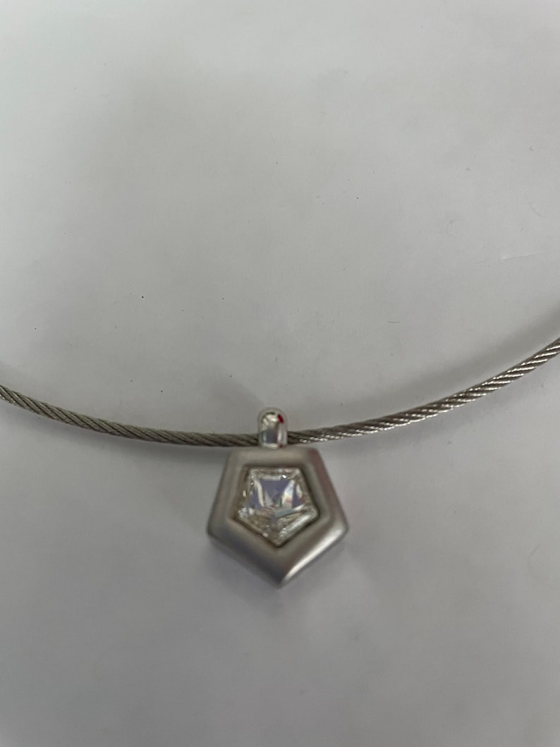 May include: A silver necklace with a geometric pendant featuring a clear crystal.