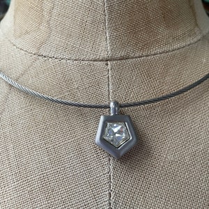 May include: A silver necklace with a geometric pendant featuring a clear crystal.