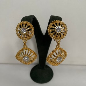 May include: Gold tone dangle earrings with a round and square design featuring clear rhinestones.