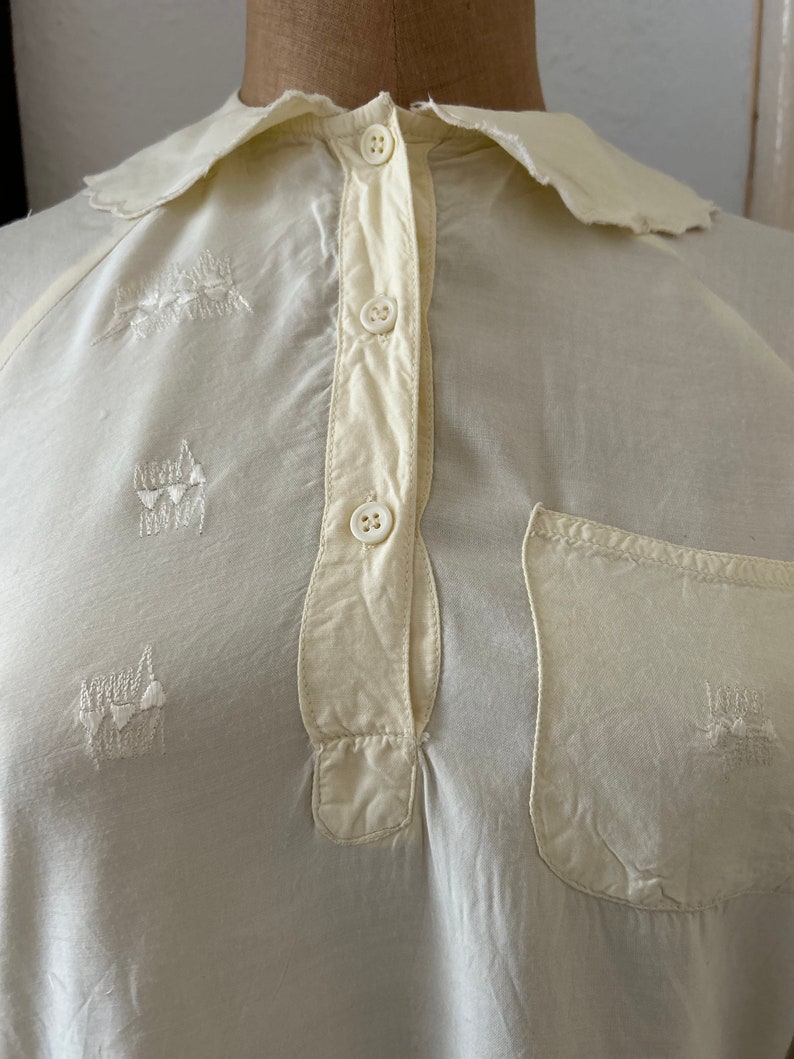 May include: A white cotton shirt with a collar and a button-up front. The shirt has a pocket on the left side and embroidered designs on the front.