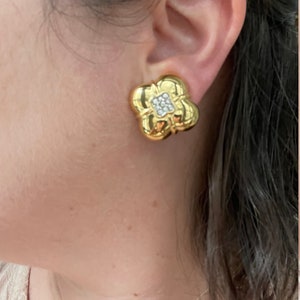 May include: Gold tone flower-shaped clip-on earrings with clear rhinestones in the center.