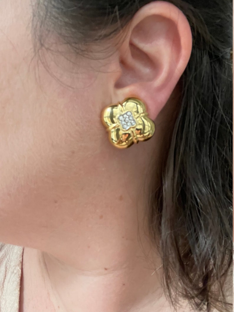 May include: Gold tone flower-shaped clip-on earrings with clear rhinestones in the center.
