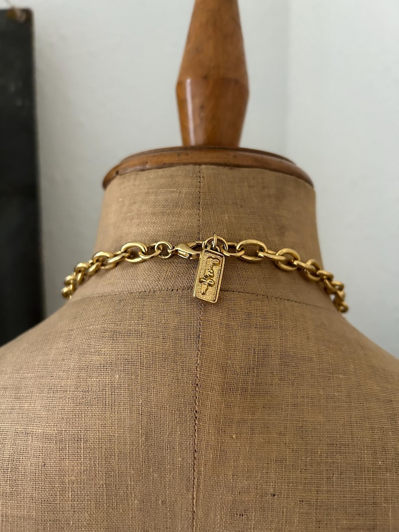 May include: A gold chain necklace with a gold tag that says "Judith Jack" hanging from it. The necklace is on a mannequin.