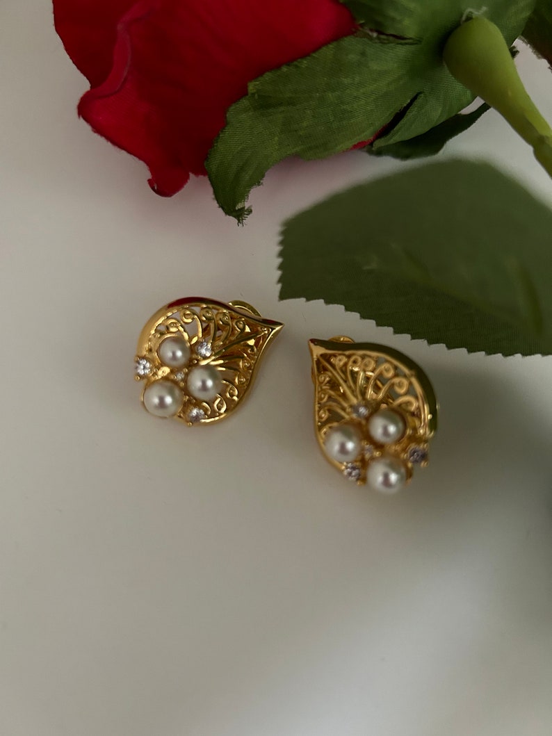 May include: A pair of gold earrings with a delicate filigree design and pearl accents.