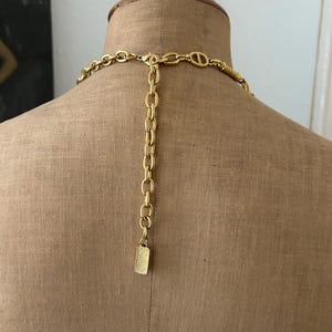 May include: Gold-toned chain necklace with a rectangular clasp. The chain is made of interlocking links.