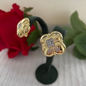 May include: A pair of gold-tone earrings with a clover design and clear cubic zirconia stones.