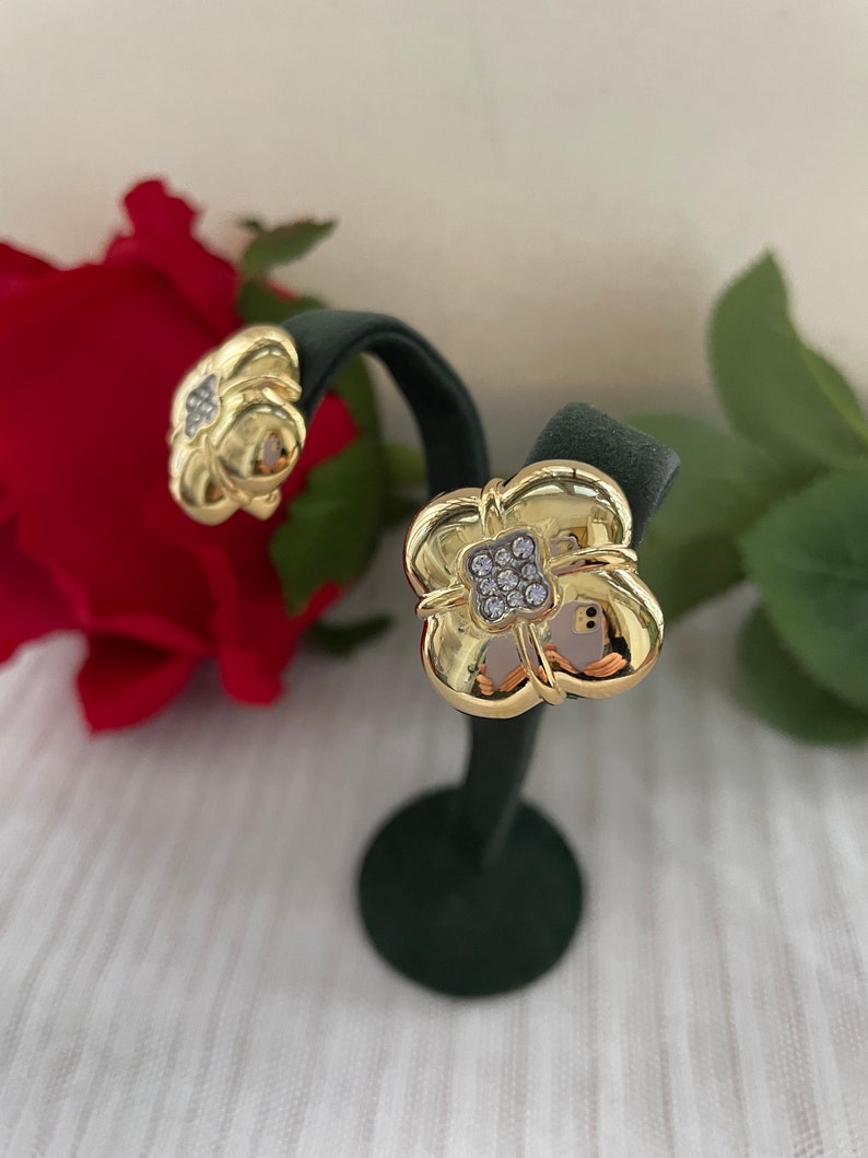 May include: A pair of gold-tone earrings with a clover design and clear cubic zirconia stones.