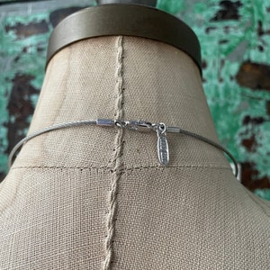 May include: A silver chain necklace with a silver clasp. The chain is made of small, round links. The clasp is a simple, rectangular design.
