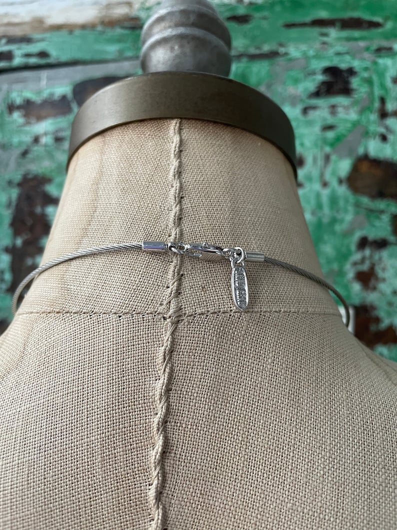 May include: A silver chain necklace with a silver clasp. The chain is made of small, round links. The clasp is a simple, rectangular design.
