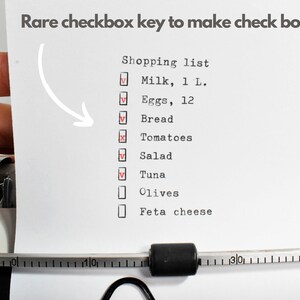 May include: A shopping list typed on a typewriter, with check boxes. The list includes milk, eggs, bread, tomatoes, salad, tuna, olives, and feta cheese. The text "Rare checkbox key to make check boxes!!" is at the top.