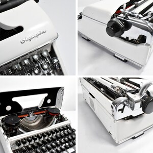May include: A white Olympia typewriter with black keys and chrome accents. The typewriter has a classic design with a carriage return lever and a paper feed mechanism. The Olympia logo is visible on the front.