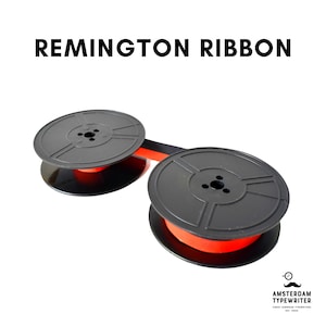 Puede incluir: Bobinas de cinta de máquina de escribir negras con una cinta naranja. La cinta está etiquetada como "Remington Ribbon".