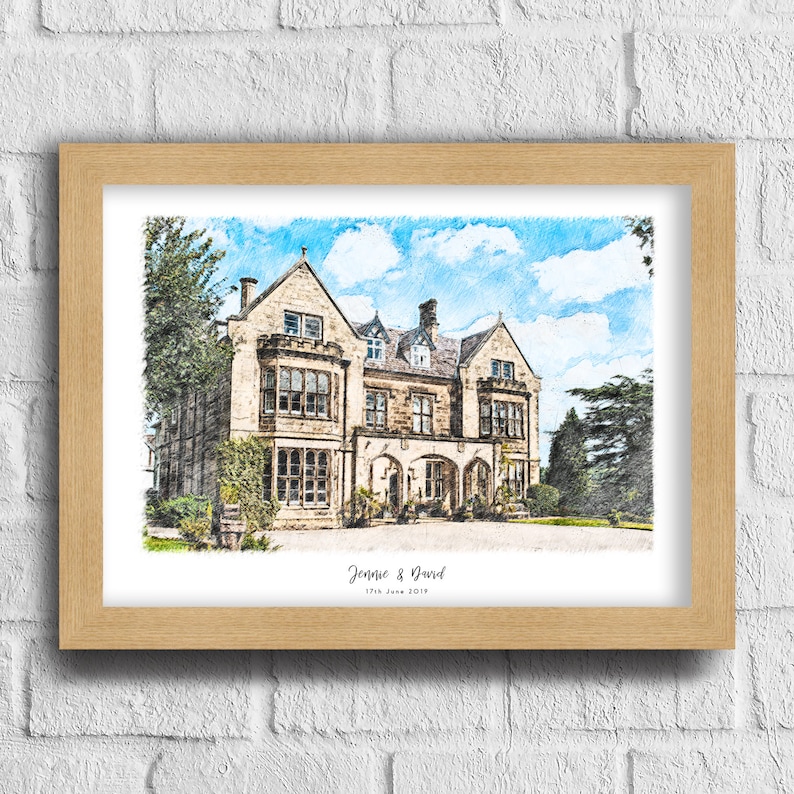 May include: A framed print of a large stone building with a blue sky and clouds in the background. The print is in a light wood frame and has the names "Jennie & David" and the date "17th June 2019" at the bottom.