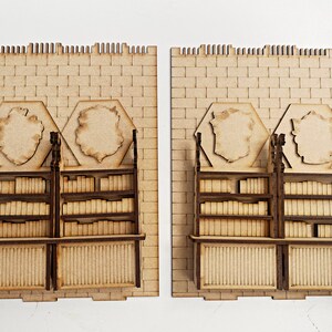 Op de afbeelding: Twee houten boekenkasten met planken vol boeken, elk met een zeshoekig decoratief paneel erboven. De boekenkasten staan tegen een bakstenen muur.