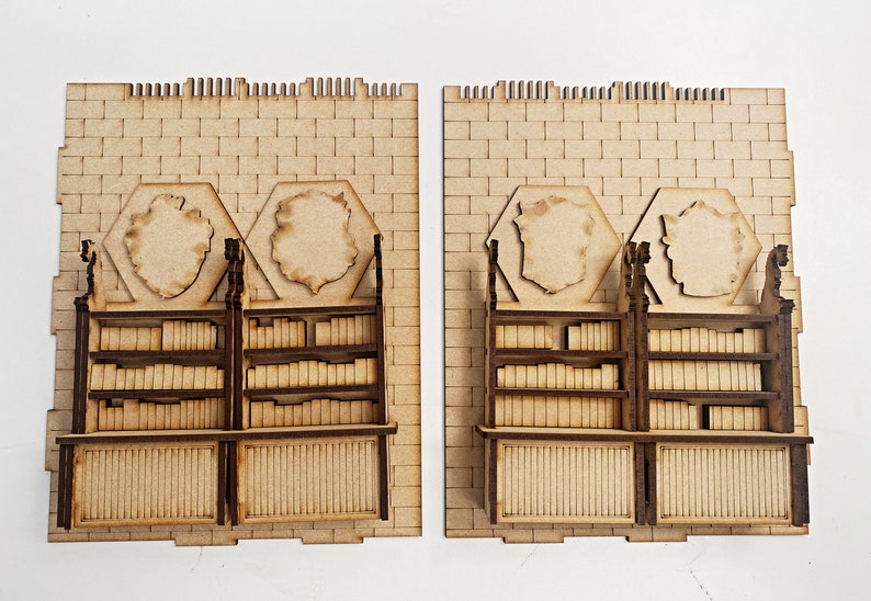 Op de afbeelding: Twee houten boekenkasten met planken vol boeken, elk met een zeshoekig decoratief paneel erboven. De boekenkasten staan tegen een bakstenen muur.