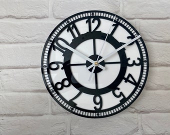 May include: A black and white clock with Roman numeral hour markers and a black center. The clock face is white with black numbers and hands.