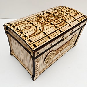 Peut inclure: Coffre en bois clair avec un motif de pentagramme sur le couvercle et les côtés. Le coffre a un dessus incurvé et le nom "Willow" est gravé. Le bois est de couleur naturelle.