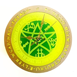 May include: A round clock with a green and yellow face featuring a pentagram and inscribed text. The clock hands are gold-colored, and the outer rim is a metallic gold. The text includes phrases like "WGAH NAGL-FHTAGN-" and "PH'NGLUI MGLW'NA FH-CTHULHU-R-LYEH".