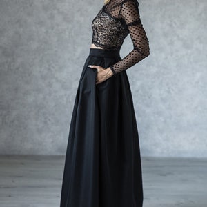 Stylish floor length black skirt with a wide pleats. Waist fit, has a sewn-in waistband about two inches wide. Made of polished cotton, with a slight sheen. Pockets in the side seams. Hidden zip fastening at the back.