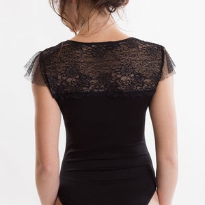 May include: Black bodysuit with a lace overlay and short sleeves.