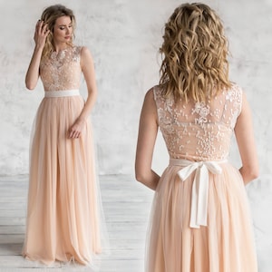 Puede incluir: Un vestido maxi de tul color melocot&oacute;n con un corpi&ntilde;o de encaje blanco y una faja de sat&eacute;n blanco. El vestido tiene un escote redondo y es sin mangas.