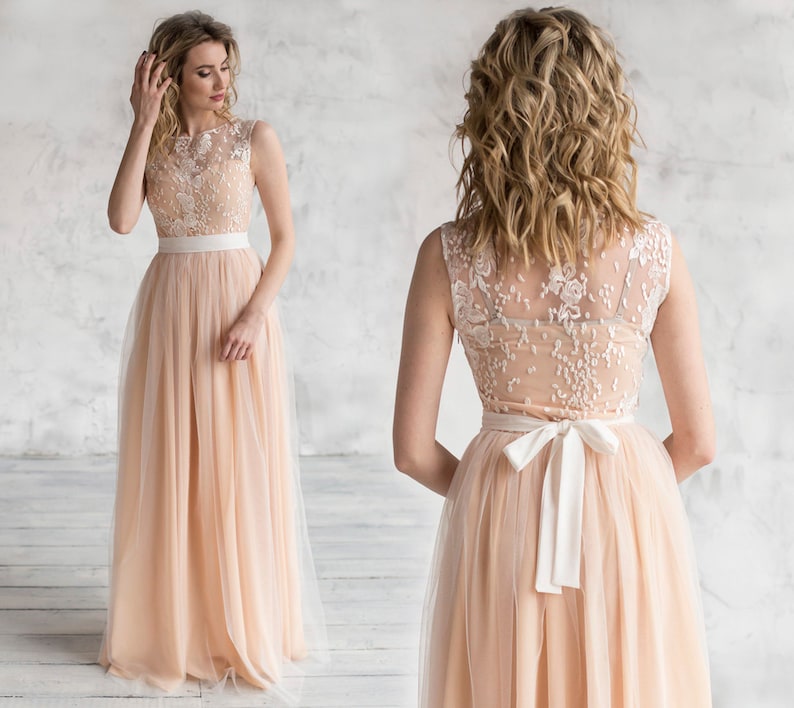 Puede incluir: Un vestido maxi de tul color melocot&oacute;n con un corpi&ntilde;o de encaje blanco y una faja de sat&eacute;n blanco. El vestido tiene un escote redondo y es sin mangas.