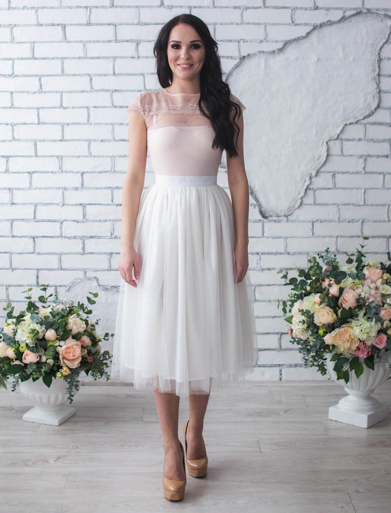 Fluffy tutu ivory tulle skirt. Midi length, waist fit. Has a sewn-in waistband about two inches wide. Sewn from several layers of soft tulle, lined with chiffon. Very flowy and airy.